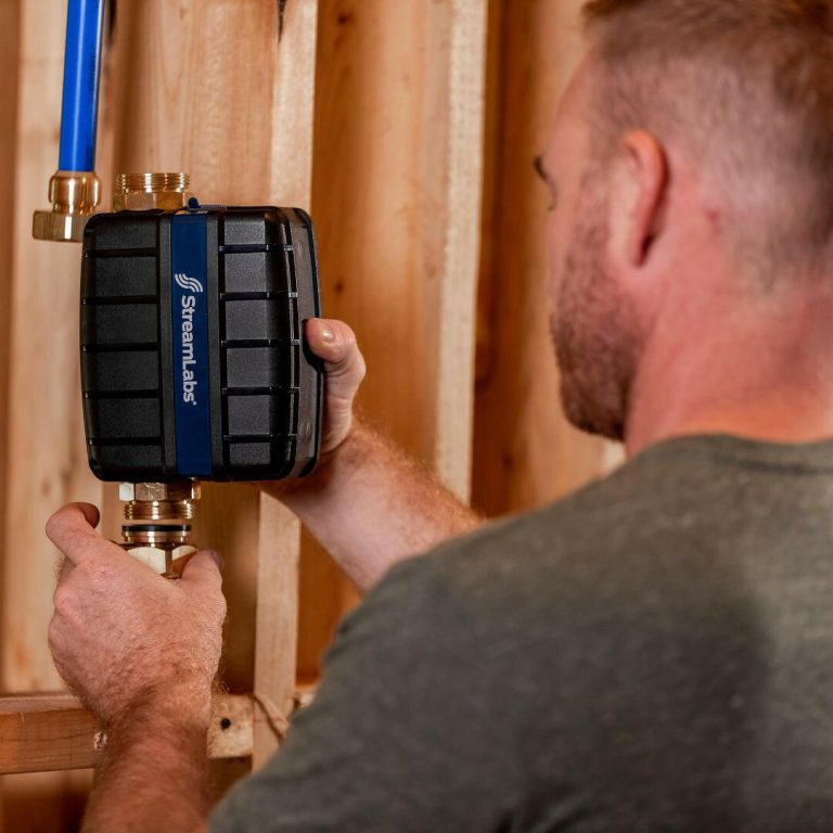 Installer mounting a StreamLabs Control on the main water line during rough-in
